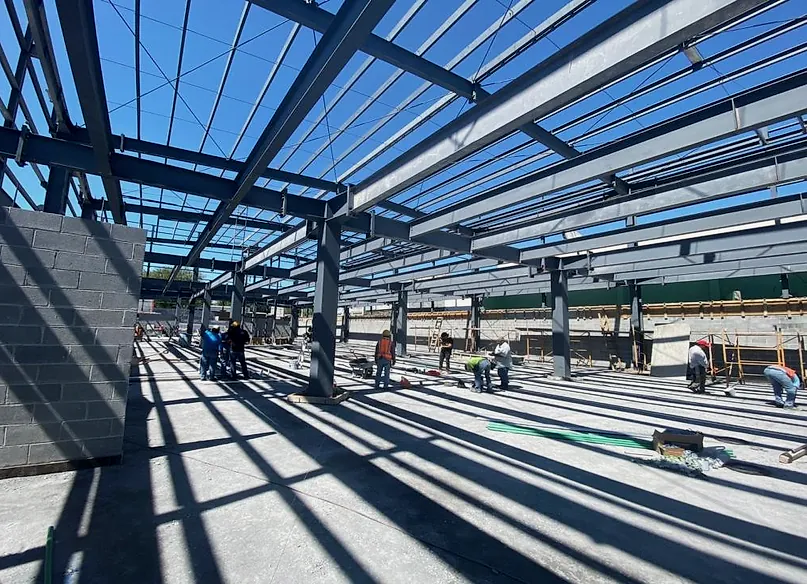 Estructura metálica de cubierta sobre columnas de acero, con la cuadrilla trabajando sobre el firme de concreto, en Elektra Reynosa
